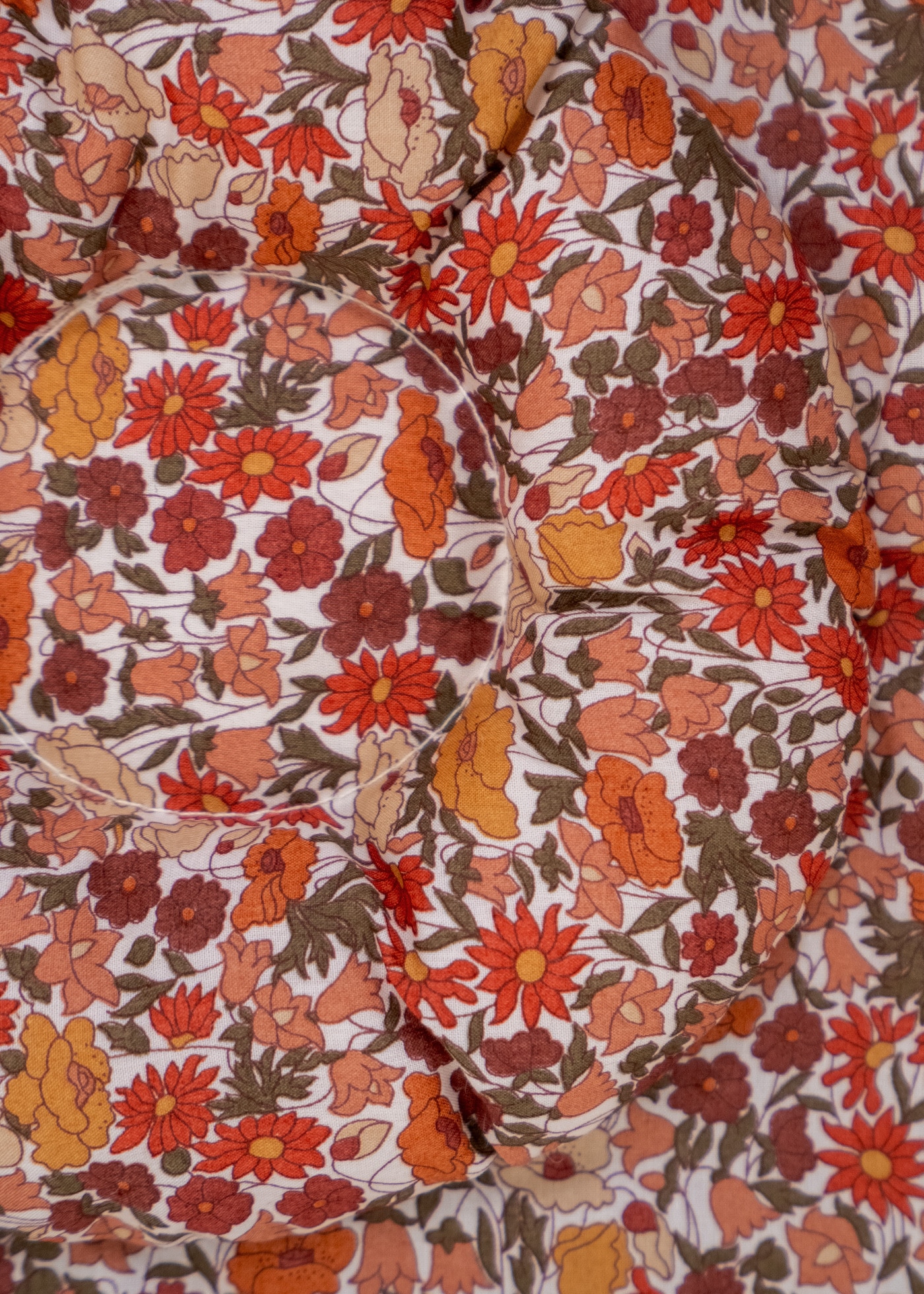 ErgoTopper Claire close-up: cotton fabric with floral pattern in red, orange, and olive, quilted padding