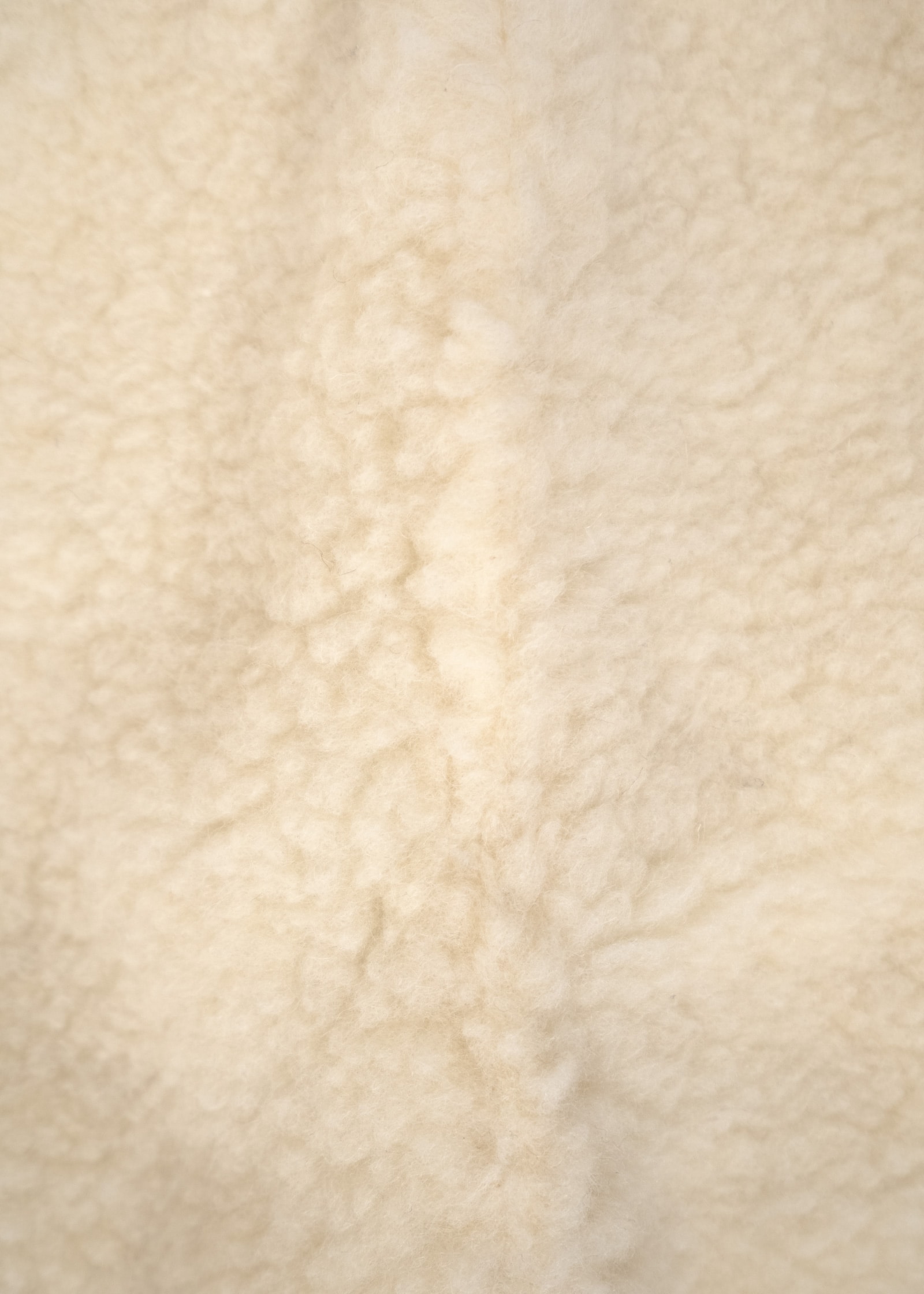 Nahaufnahme von naturweißem Wollvlies als Innenfutter des ANGELCAB Handmuffs