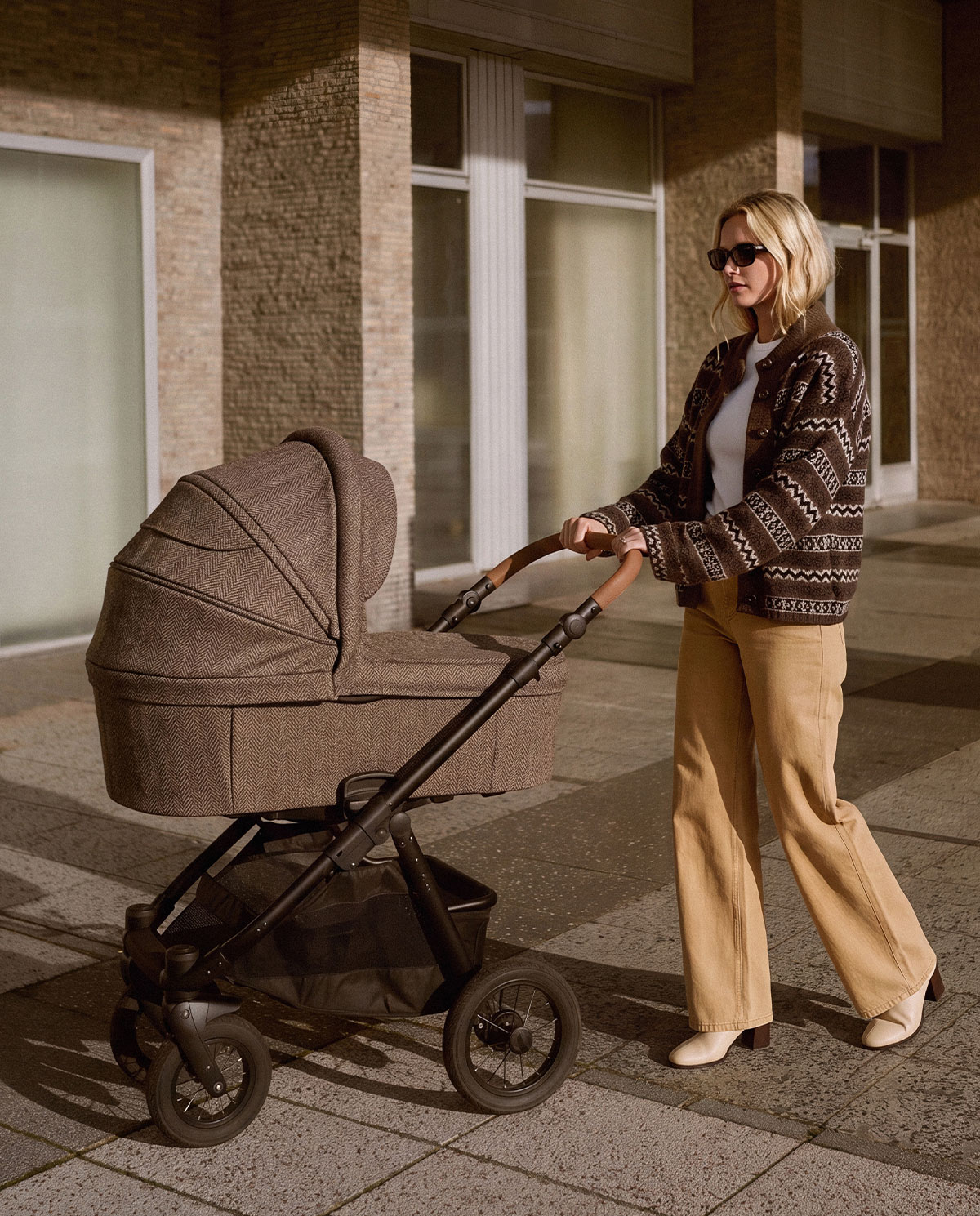 Harris Tweed Wanne im Alltag Frau schiebt Kinderwagen mit Textilwanne aus Harris Tweed im Fischgrat-Muster, schwarzes Gestell, Ledergriff