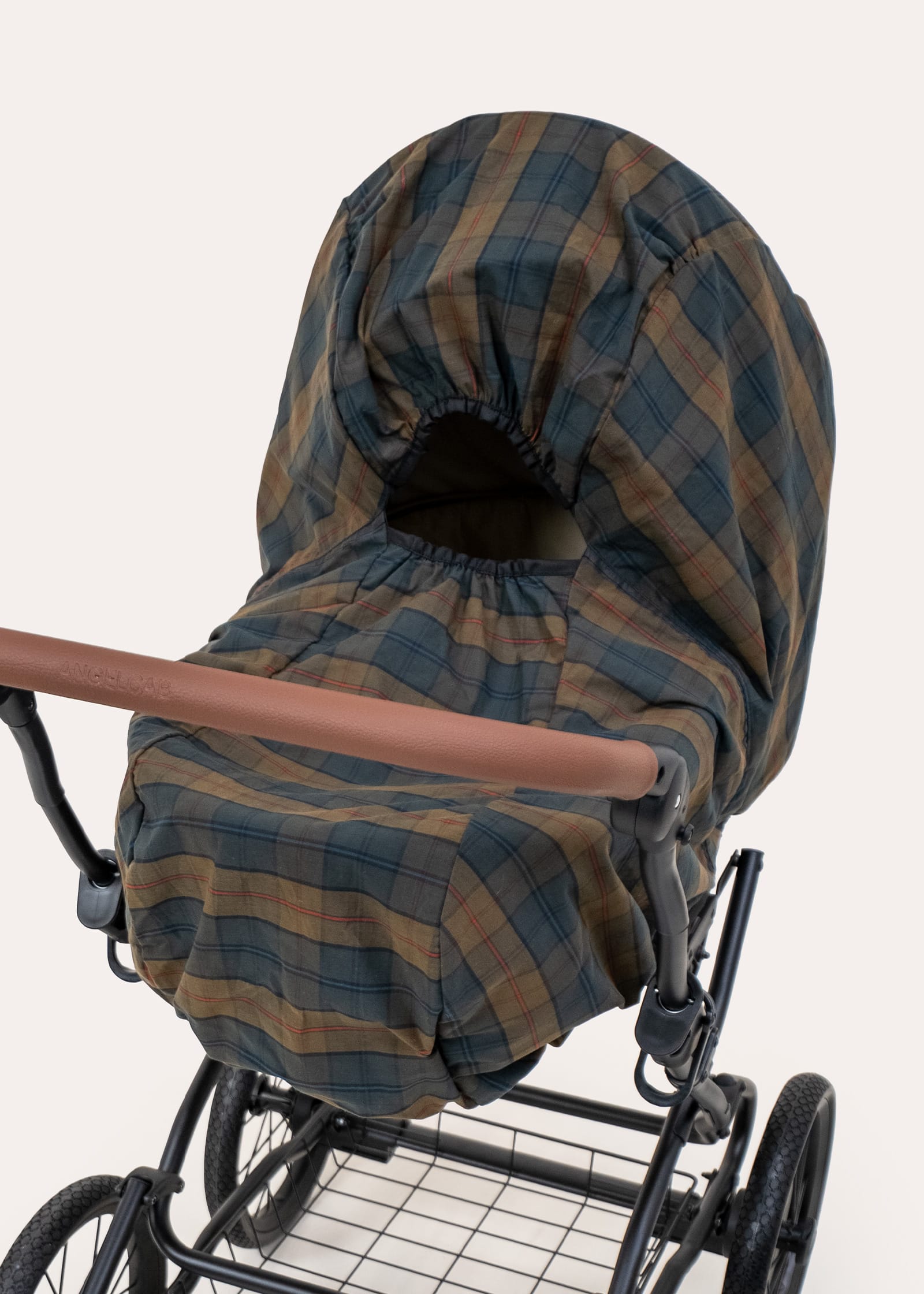 Regenhaube aus gewachster Baumwolle im Karomuster über Kinderwagenwanne, schwarzes Gestell mit Ledergriff